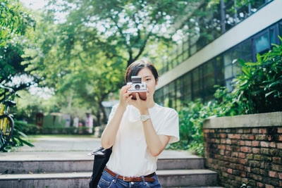 女人在白色t恤使用相机
